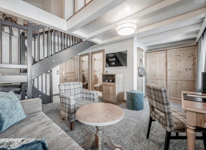 Maisonettenzimmer im Hotel Jenewein in Obergurgl Ein helles Maisonettenzimmer mit zwei Ebenen, Sitzbereich, Holzschränken und einer Treppe im Hotel Jenewein.