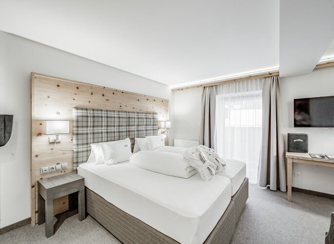 Zirbenzimmer im Hotel Jenewein in Obergurgl Ein helles Zirbenzimmer mit Doppelbett, Holzkopfteil und Fenster im Hotel Jenewein.