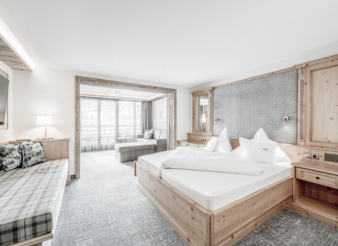 Juniorsuite im Hotel Jenewein in Obergurgl Die Juniorsuite im Hotel Jenewein zeigt ein helles Schlafzimmer mit Sitzecke und viel Holz.