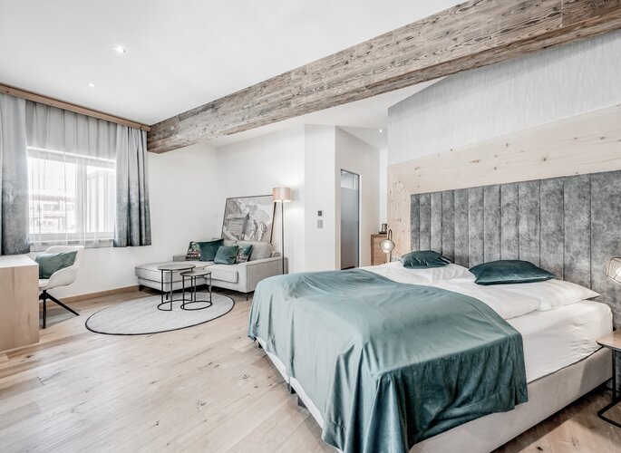 Komfortzimmer im Hotel Jenewein in Obergurgl Helles Komfortzimmer mit Doppelbett, Sitzecke und sichtbaren Holzbalken im Hotel Jenewein in Obergurgl.