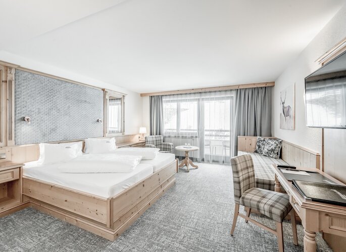 Doppelzimmer mit Balkon und Bergblick in Obergurgl Helles Doppelzimmer mit Holzmöbeln, zwei Betten und Sitzbereich vor dem Balkon.