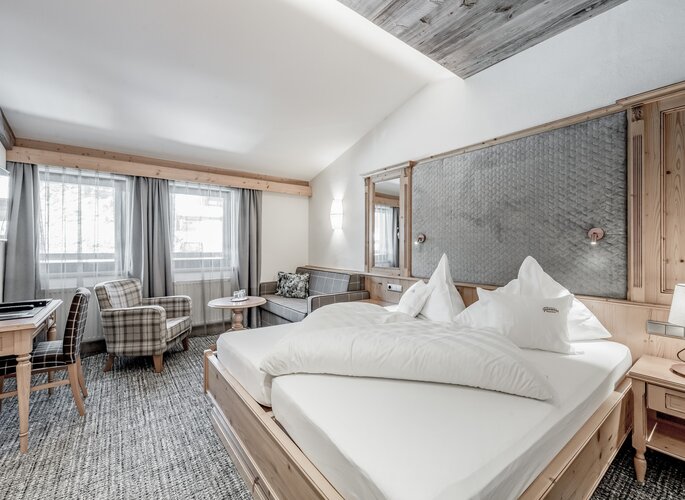 Studio Obergurgl im Hotel Jenewein Ein helles Studio mit Doppelbett, Sitzecke und großen Fenstern im Hotel Jenewein.