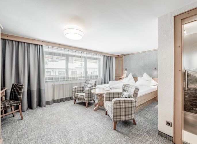 Doppelzimmer im Hotel Jenewein in Obergurgl Gemütliches Doppelzimmer im Hotel Jenewein mit Sitzbereich, großen Fenstern und klassischem Ambiente.