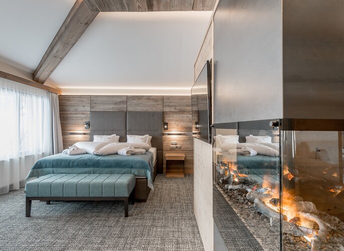Romantikzimmer mit Kamin im Hotel Jenewein Ein modernes Romantikzimmer mit Doppelbett, Sitzbank und Kamin im Hotel Jenewein.